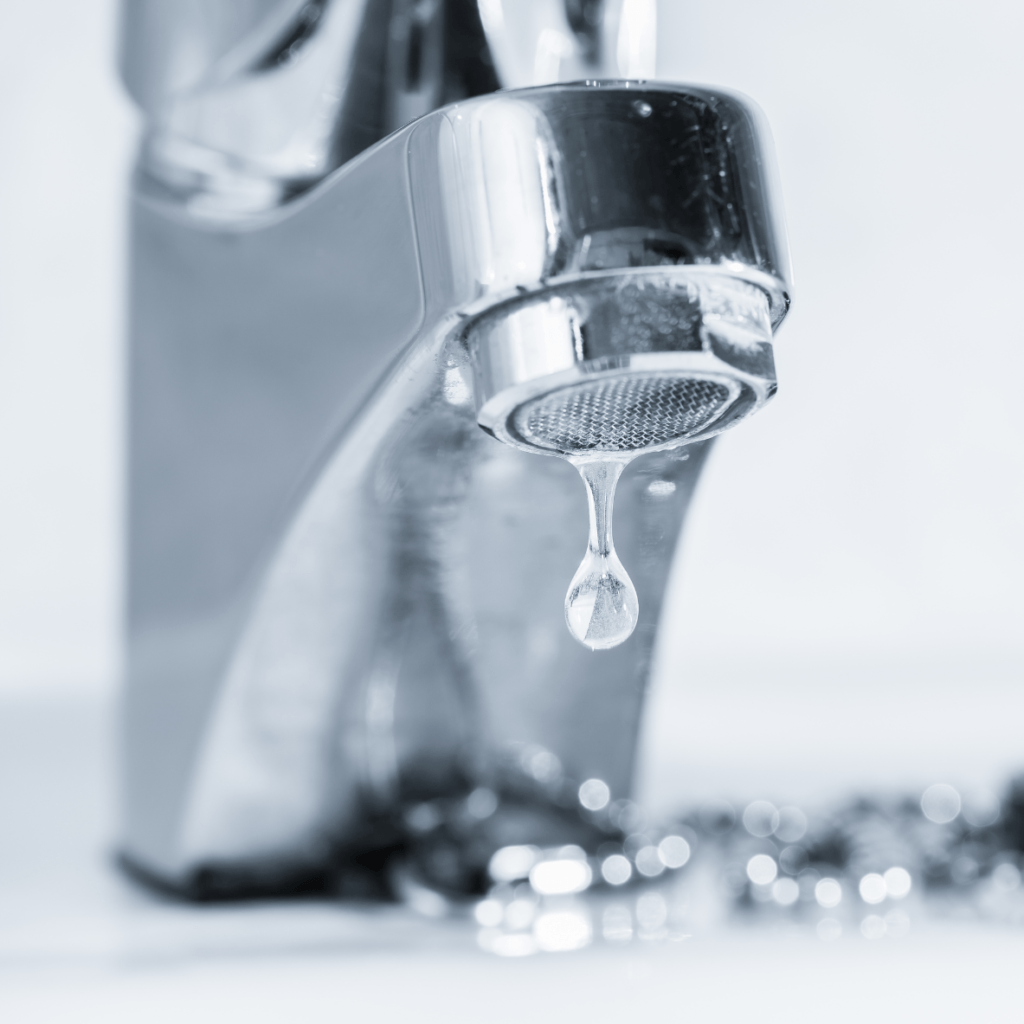 Old faucet leaking from spout in a bathroom, presented in black and white.