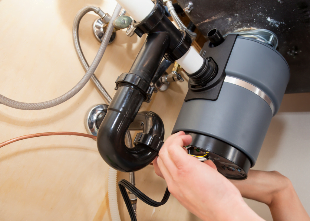 Man installing a new garbage disposal unit under the kitchen sink at home